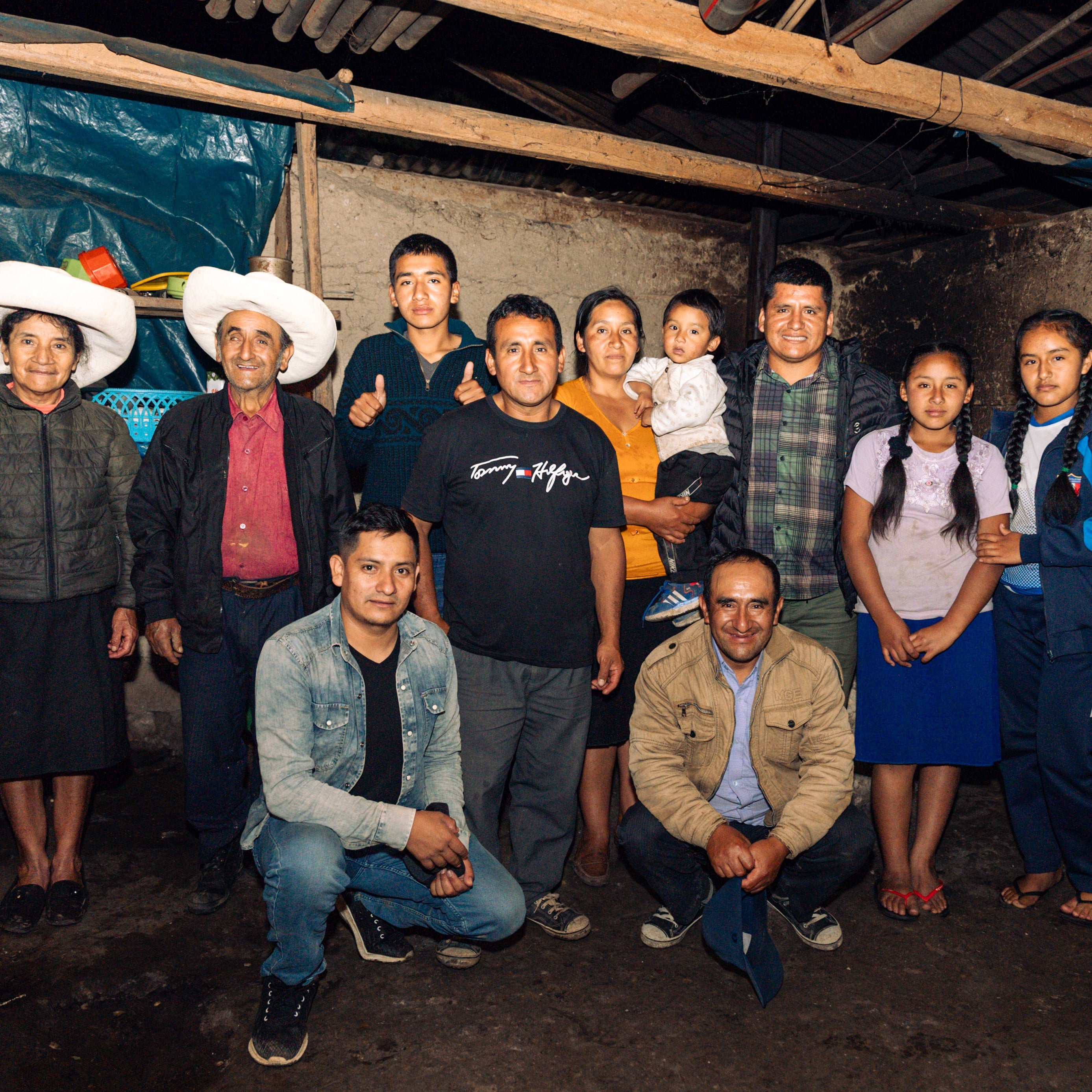 Group of people posing together in a rustic indoor setting with blue tarp walls.