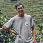 Man wearing a gray t-shirt with a logo in a coffee plantation