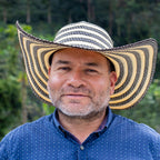 Man wearing a striped cowboy hat with a blurred green background