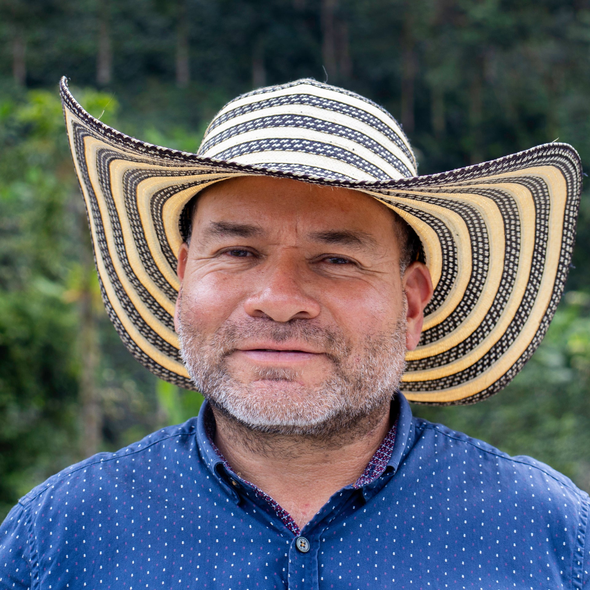 Man wearing a striped cowboy hat with a blurred green background