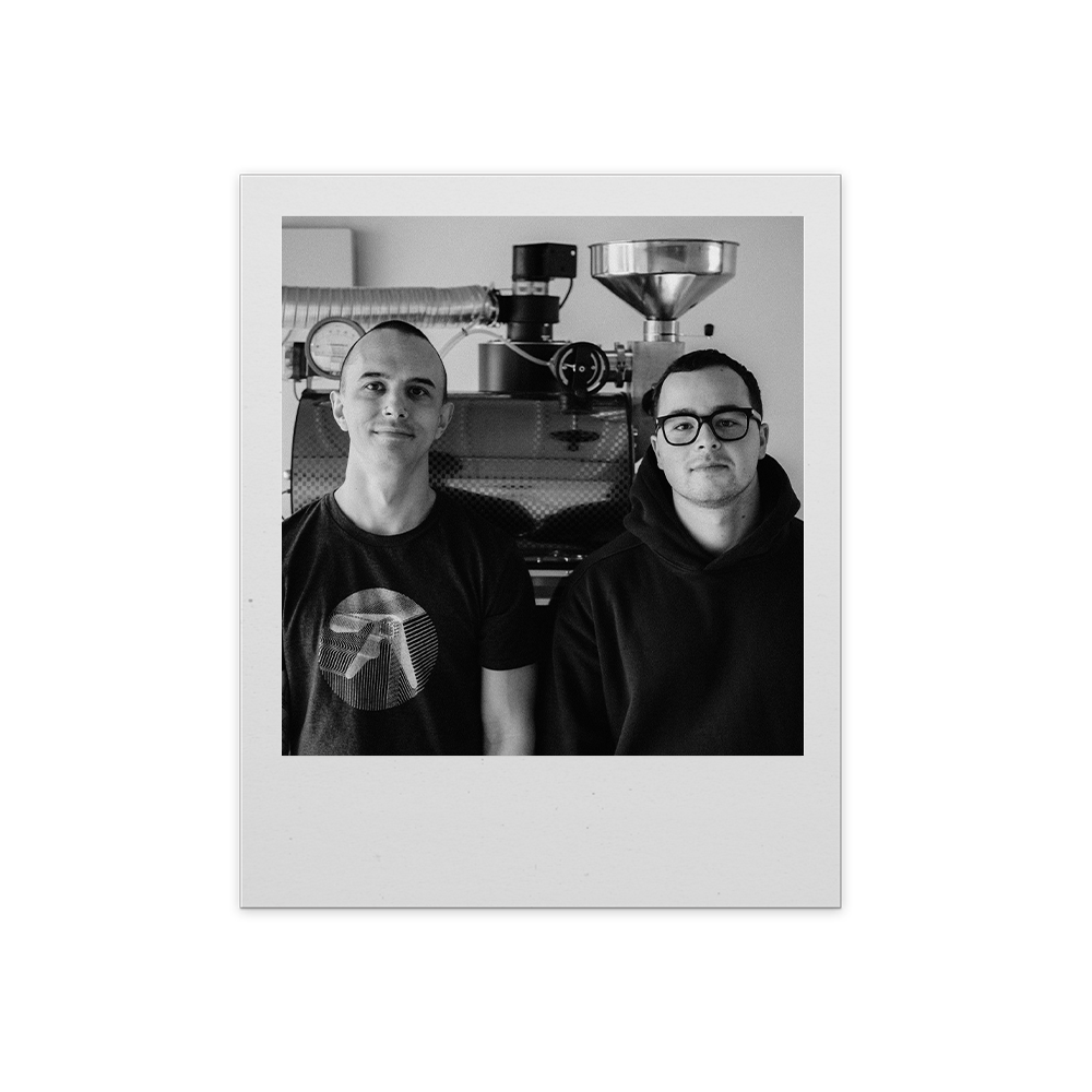 Two people posing together in a casual setting with a white border.